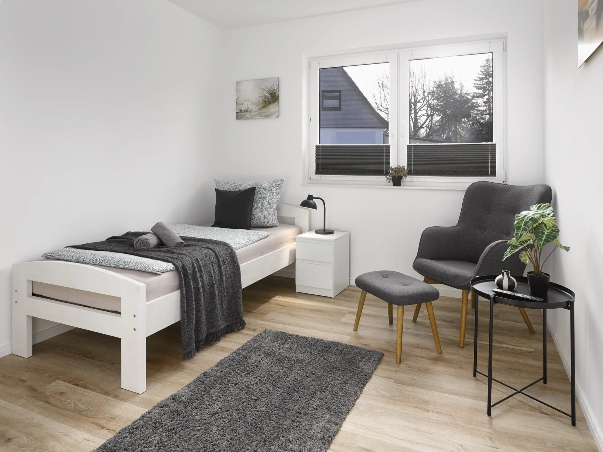 Helles Einzelzimmer mit Bett, Sessel und Fenster